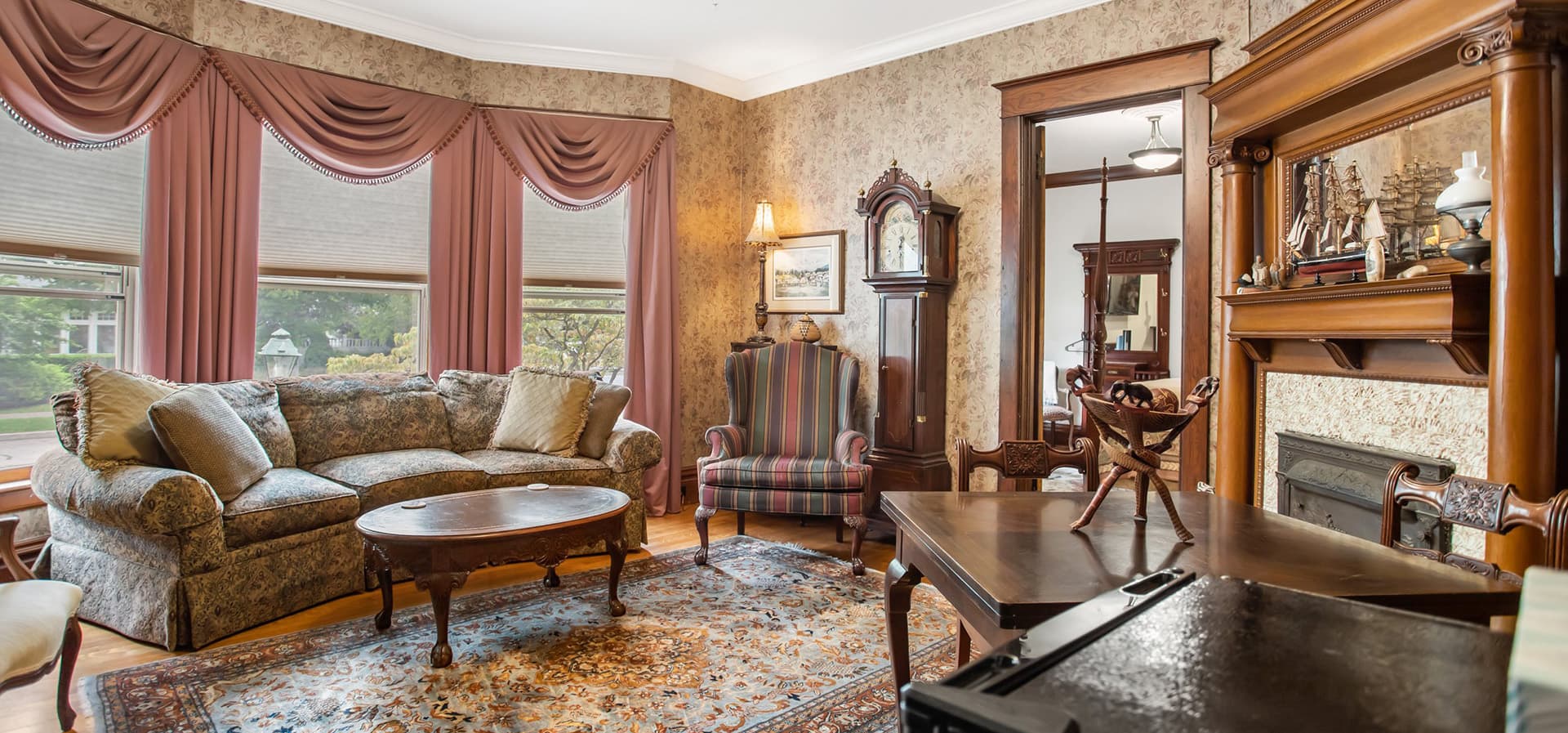 Cozy living room featuring vintage furniture, decorative curtains, and a classic clock.